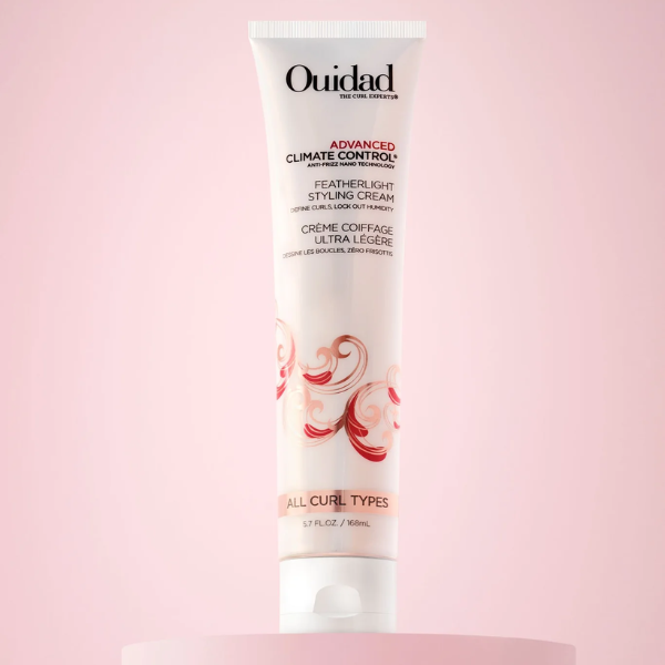 Ouidad Advanced Climate Control Styling Cream in een studo met roze achtergrond