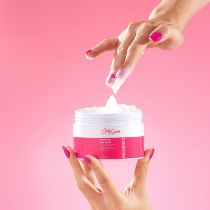 Iemand die die substantie laat zien van de Curly Secret Repairing Hair Mask door het eruit te halen.