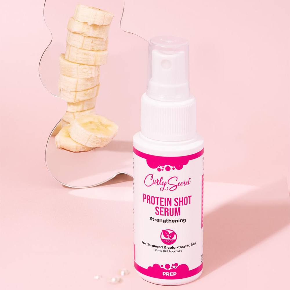 Protein Shot Serum van Curly Secret in sfeerfotografie met roze achtergrond en banaan